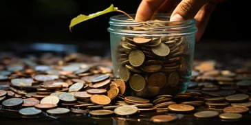 a hand putting a leaf into a jar of coins