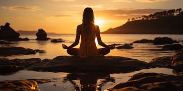 a person sitting on a rock in front of water with a sunset