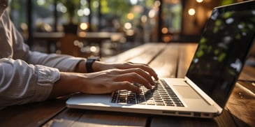 A man typing on a laptop in a restaurant